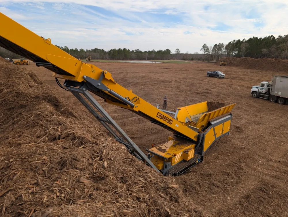 Portable trommel screen turning leaves and branches into compost-ready material